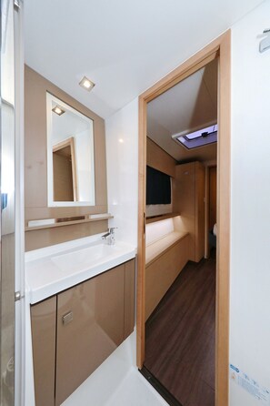 A compact bathroom with a white sink, mirror, and wooden cabinets. - Sun-kissed Sailing Adventure in Split-Dalmatia, Croatia (Trogir)