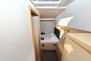 Una habitación pequeña y luminosa con tragaluces, una cama, una mesita y un armario.