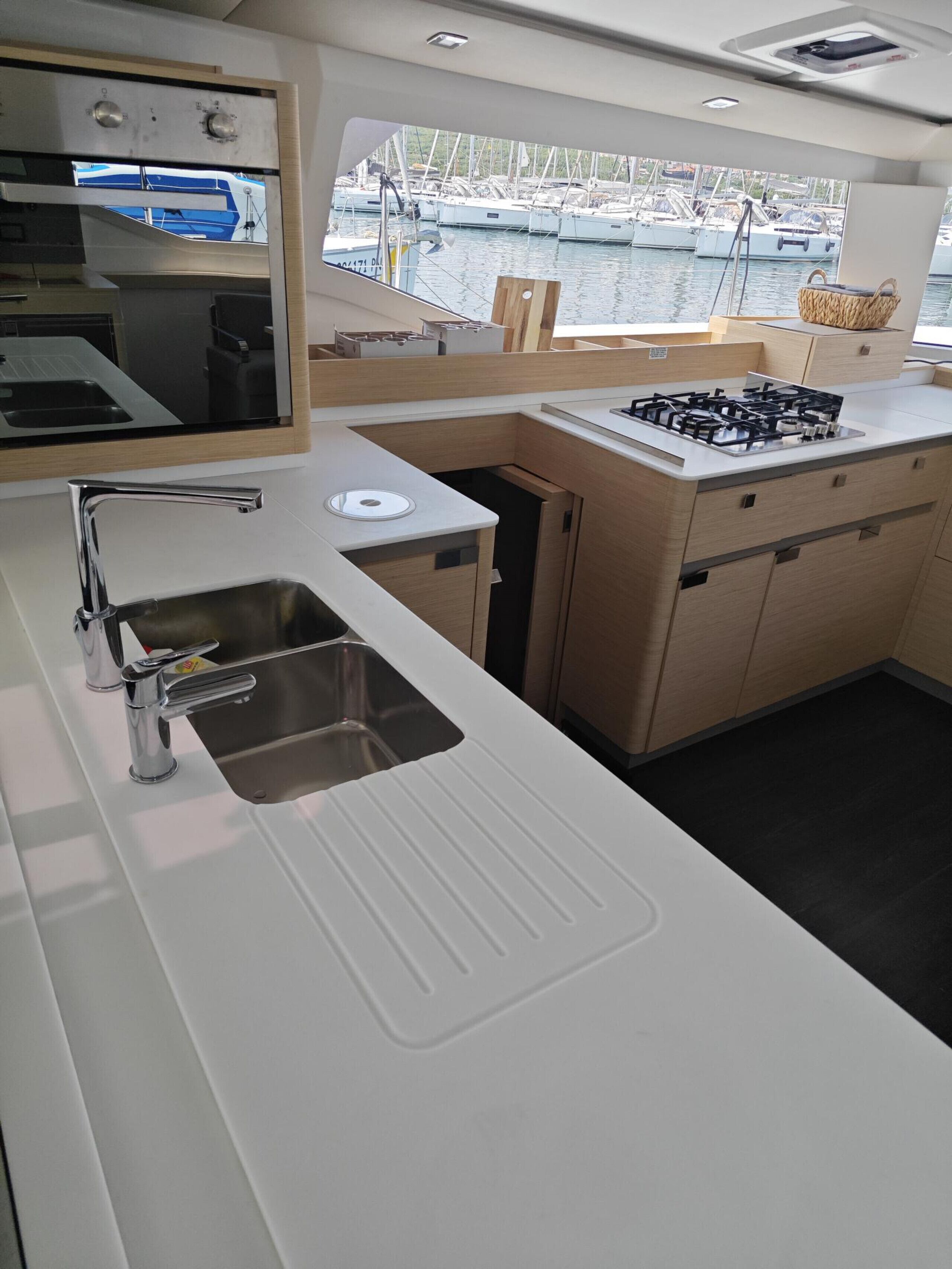 A modern kitchen with a sink, stove, and window overlooking a marina.