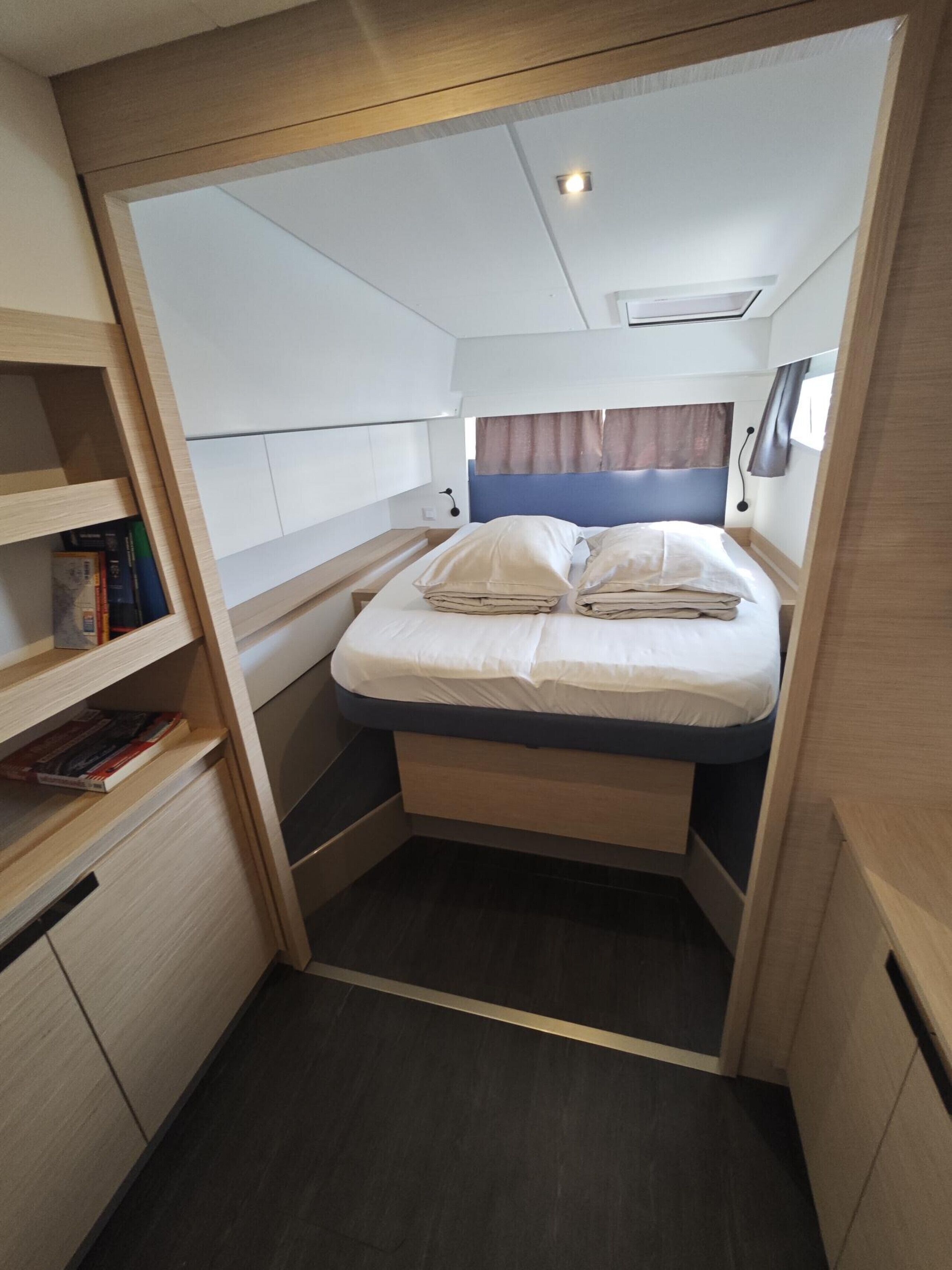 A compact, well-lit room with a bed, built-in storage, and a small seating area.