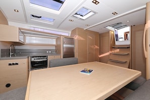A compact kitchen with a built-in oven, a dining table, and a small seating area. - Sibenik Sun and Beach Sailing Extravaganza: A Croatian Coastal Adventure (Vodice)