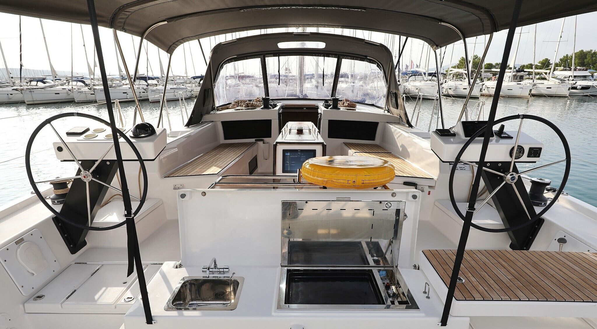 A boat's deck with a steering wheel, navigation system, and a small sink.