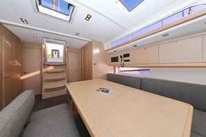 A compact interior with a dining area, seating, and a small kitchenette. - Sibenik Sun and Beach Sailing Extravaganza: A Croatian Coastal Adventure (Vodice)