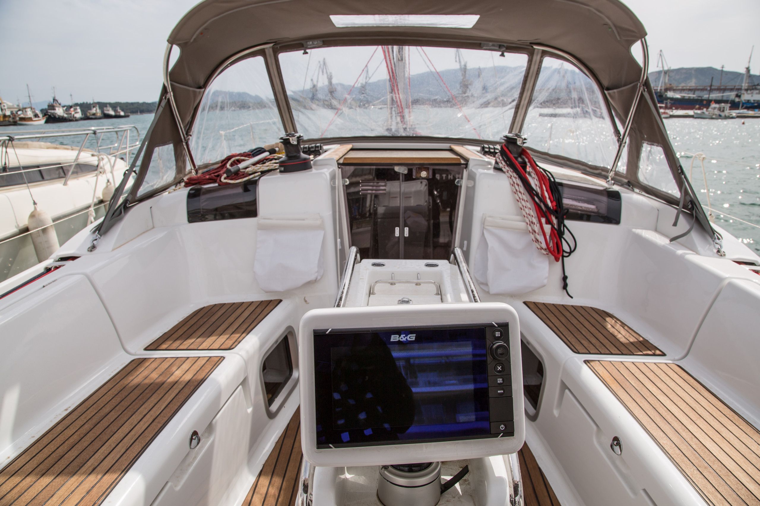 L'intérieur d'un bateau équipé d'un système de navigation B&G, d'un pont en bois et offrant une vue sur le port de plaisance.
