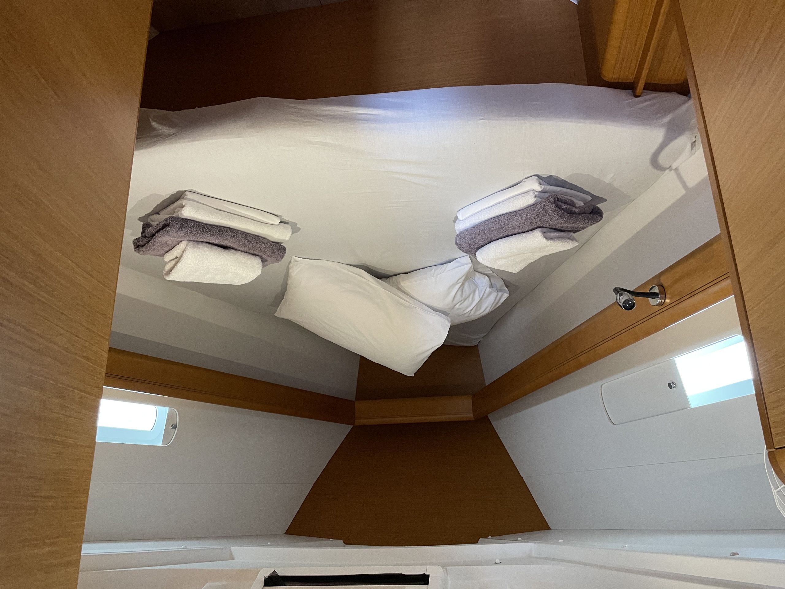 A compact, well-lit interior space with a bed, pillows, and neatly folded towels.