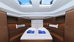 Een smal, houten interieur met een bed, dakramen en inbouwopbergruimte.