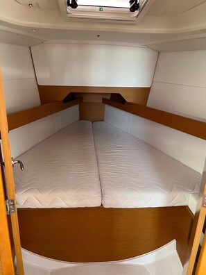 A compact boat interior with a central sleeping area, wooden headboards, and a small overhead window. - Sun-Kissed Sailing Adventure in Zadar, Croatia (Bibinje)