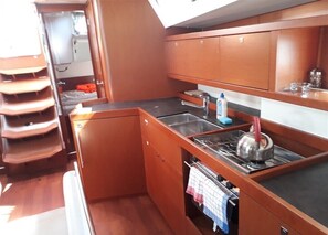 Uma cozinha compacta com armários de madeira, pia, fogão e um pequeno balcão.