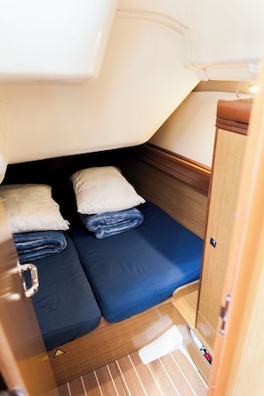 A compact sleeping area with two beds, a wooden cabinet, and a small storage space. - Sun-kissed Sailing Adventure in the Ionian Islands (Preveza)