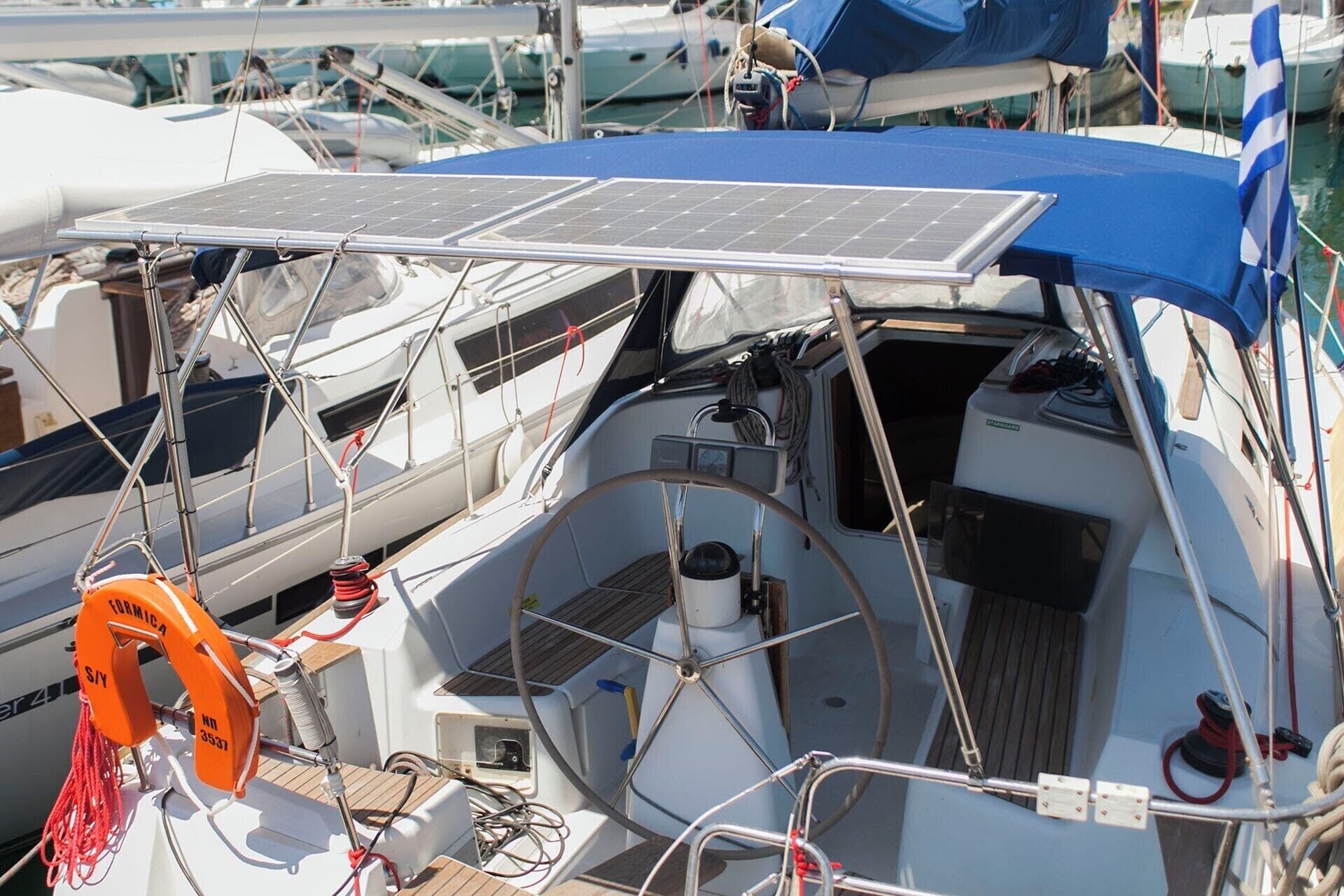 Eine Segelyacht mit blauem Sonnensegel, einem Rettungsring und einem Solarmodul.