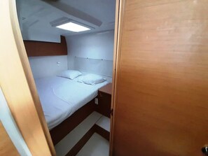 Ein kleines Zimmer mit Etagenbett, einem Nachttisch, einer Deckenleuchte und einer Tür.