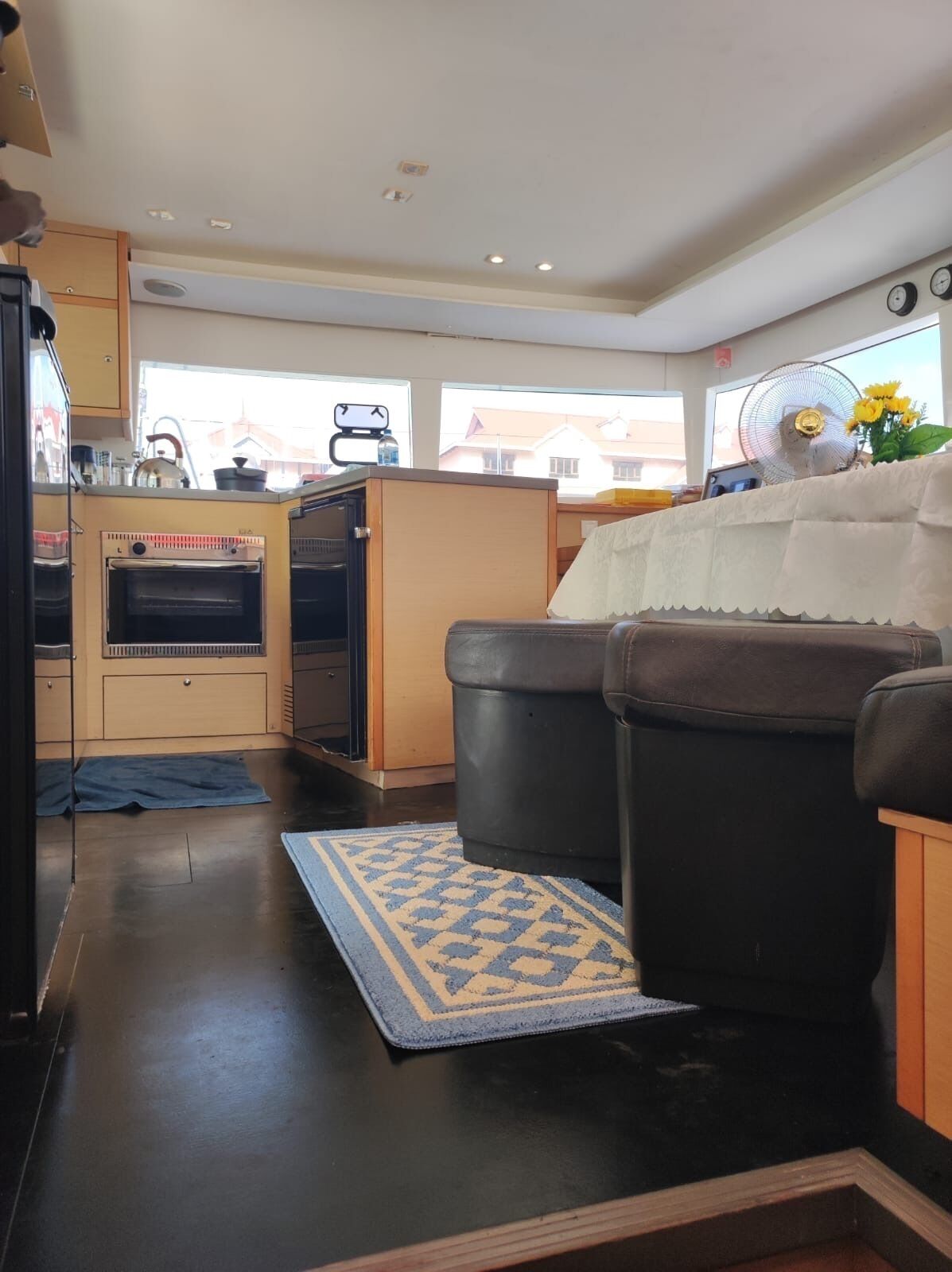 Een ruimtelijk ingerichte leefruimte met kitchenette, een bank en een ventilator.
