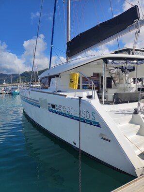 A white yacht docked at a marina with a cabin, deck, and a life ring visible.