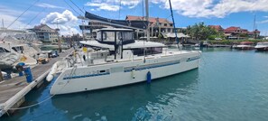 A marina with a white yacht docked at the pier, surrounded by buildings and other boats.