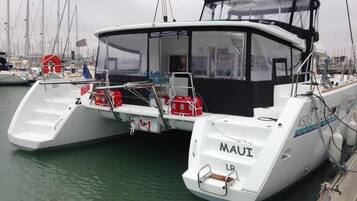Um barco branco atracado em um porto, com o nome 'Maui' na popa.