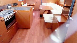 A compact interior with a kitchenette, a dining area, and a seating space. - Sun-soaked Sailing Adventure in the Ionian Islands (Perigiali)