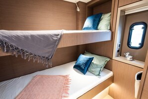 A bunk bed with a window, a small shelf with a decorative item, and a light fixture.