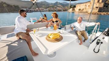 Um barco com uma mesa posta para quatro pessoas, uma garrafa de BALI e um prato de bananas.