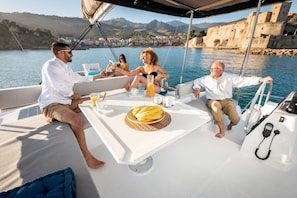 A boat with a table set for four people, a bottle of BALI, and a plate of bananas.