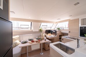 Una piccola cucina compatta con un tavolo da pranzo per due persone, un angolo cottura e una finestra con vista sul porto.