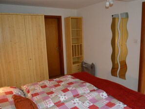 A bedroom with a bed, a wardrobe, a built-in shelf unit, and a mirror on the wall. - Oehrli Appartement/Fewo, Dusche oder Bad, WC 4-Bettwohnung by Interhome (Gstaad)