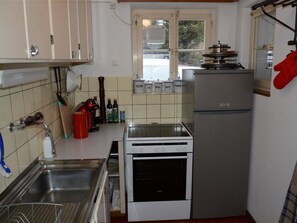 A kitchen with a stove, refrigerator, and a window. - Oehrli Appartement/Fewo, Dusche oder Bad, WC 4-Bettwohnung by Interhome (Gstaad)