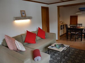 Una sala de estar con sofá, mesa de centro y comedor con mesa y sillas.