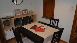 Ein Essbereich mit Tisch, Stühlen, einem Holzschrank und einem Spiegel.