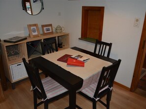 A dining area with a table, chairs, a wooden cabinet, and a mirror. - Oehrli Appartement/Fewo, Dusche oder Bad, WC 4-Bettwohnung by Interhome (Gstaad)