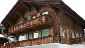 Ein mehrstöckiges Holzgebäude mit Balkonen und grünen Fensterläden.