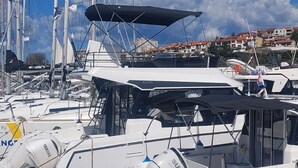 Un port de plaisance où sont amarrés de nombreux yachts, avec leurs mâts et leurs voiles bien visibles, le tout sur fond de bâtiments.
