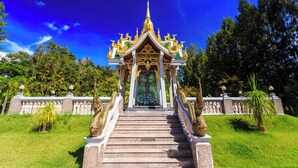 Um templo com uma escadaria que leva a uma entrada com telhado dourado, cercado por vegetação.