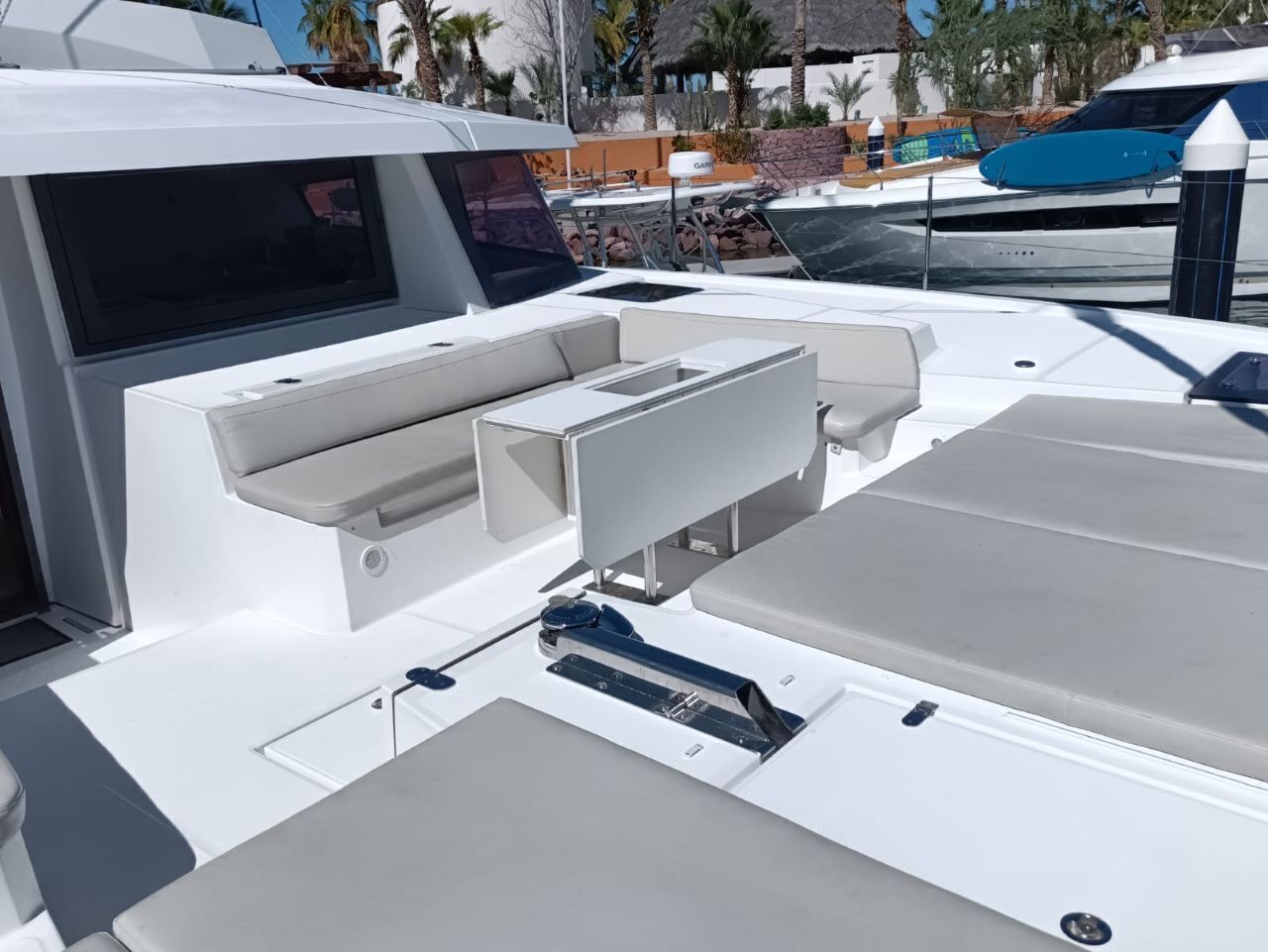 A boat's deck with seating, a control panel, and a window.