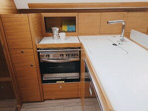 Eine kleine Küche mit Holdekor-Schränken, einem eingebauten Backofen und einer weißen Arbeitsplatte.
