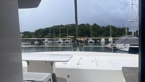 Ein Yachthafen mit vertäuten Booten, ein klarer Himmel und eine Blick auf bewaldetes Gebiet im Hintergrund.