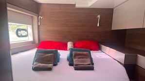 Ein Bett mit zwei Kissen, ein Fenster mit Blick und ein Holz-Kopfstück.