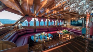 A luxurious cabin with a wooden interior, a bar area, and a large window offering a view of the sea. - Sun-Kissed Sailing Adventure in Split, Croatia (Kaštel Gomilica)