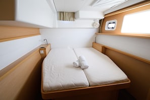 Eine gemütliche Kabine mit einem Einzelbett, Holz-Kopfteilen und einem Fenster.