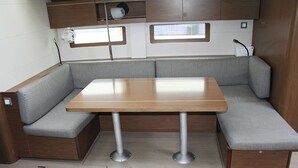 Interior compacto de una autocaravana con una mesa de madera y asientos acolchados grises.