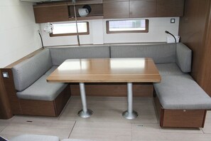 Ein kompaktes Wohnmobil-Interieur mit Holztisch und grau gepolsterten Sitzgelegenheiten.