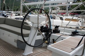 A boat's deck with a steering wheel, cushioned seating, and a wooden deck. - Dubrovnik Delight: A Sun-Kissed Sailing Experience (Komolac)