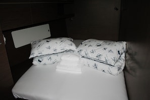A bed with white bedding and pillows featuring a nautical pattern, a folded white towel, and a wooden headboard. - Dubrovnik Delight: A Sun-Kissed Sailing Experience (Komolac)
