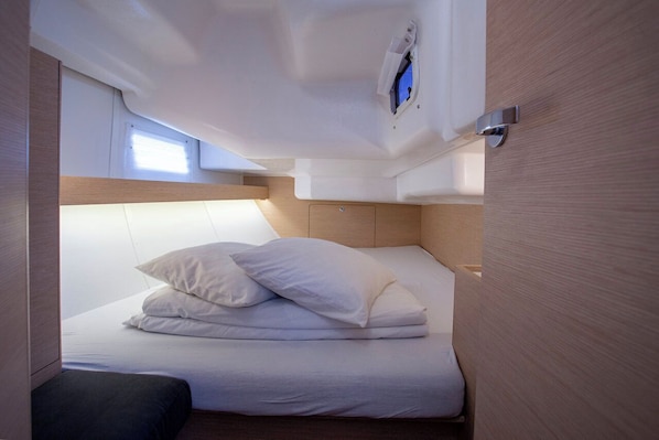Una cabana compacta i ben il·luminada amb un llit superposat, una finestra petita i una làmpada de sostre.