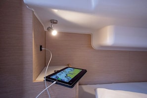 Ein Tablet auf einem Nachttisch, darüber eine Wandlampe.