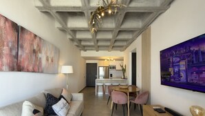 Een moderne woonkamer met een bank, een eettafel met stoelen, een televisie en kunstwerken aan de muren.