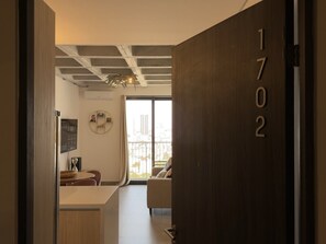 Ein modernes Interieur mit einer Holztür, auf der '1702' steht, einem Essbereich mit Tisch und Stühlen sowie einem Ausblick durch ein großes Fenster.