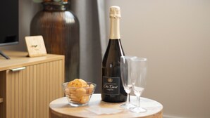 A wooden table with a bottle of champagne, two glasses, a bowl of cookies, and a vase with orange flowers. - 3-room apartment in the historic Cordiers district, right in the heart of the city; 2 bedrooms, 2 bathrooms, with private parking included (Le Tréport)
