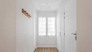 A hallway with a wooden floor, white walls, and a double door with frosted glass panels. - 3-room apartment in the historic Cordiers district, right in the heart of the city; 2 bedrooms, 2 bathrooms, with private parking included (Le Tréport)