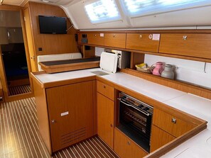 A compact kitchenette with a microwave, oven, and storage cabinets. - Sun-Kissed Sailing Adventure in Istria, Croatia (Vrsar)