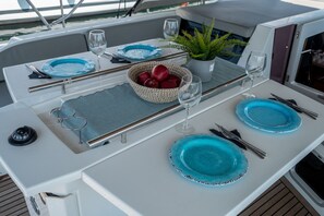 A dining table with blue plates, cutlery, and a bowl of red apples. - Sun-Kissed Sailing Adventure in the Ionian Islands, Lefkada (Lefkada)